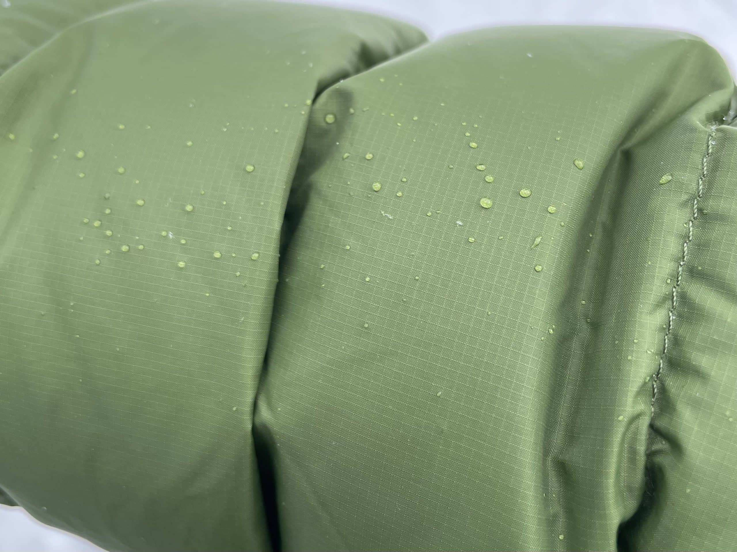 A closeup image of water beading on the fabric of a Stio Hometown Down hooded jacket.