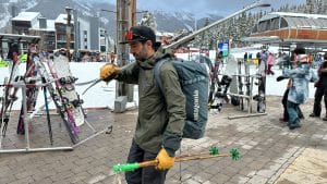 Image of a man carrying skis and a Patagonia Black Hole Duffel 70L as a backpack.