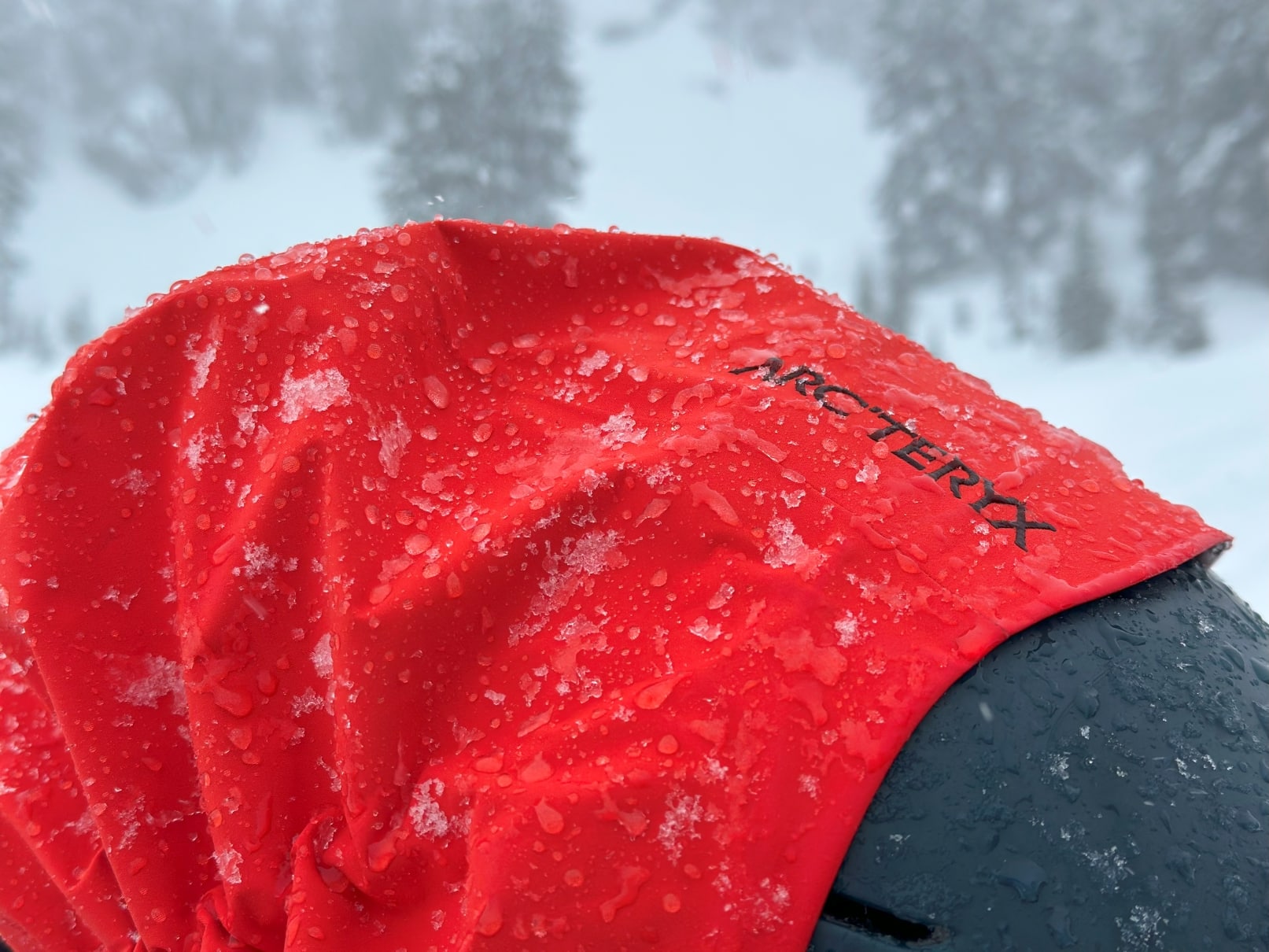 A closeup image of the hood on an Arc'teryx Rush jacket covered in melting snow.