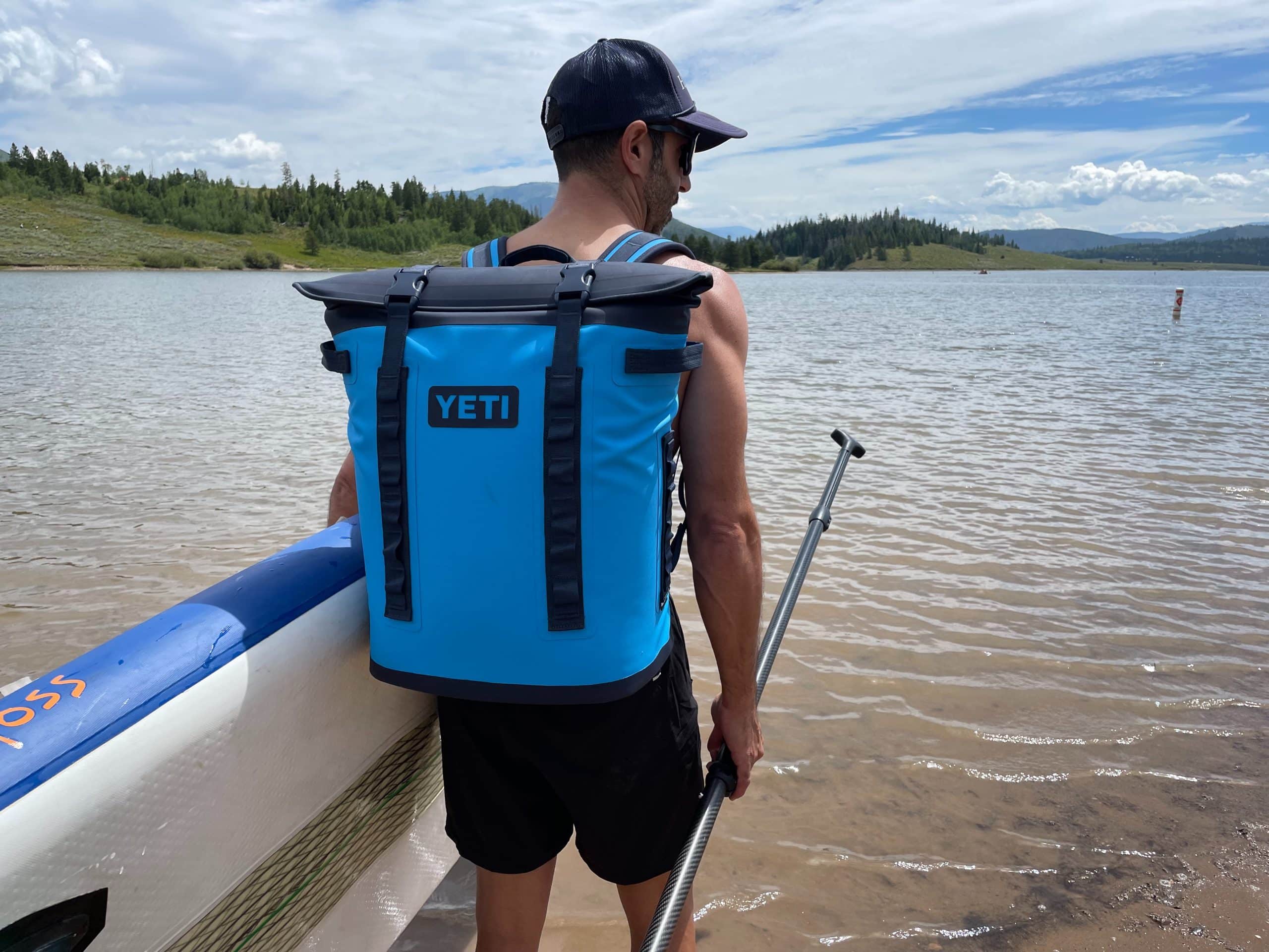 Wearing the YETI Hopper m20 backpack cooler on the shore of a lake.