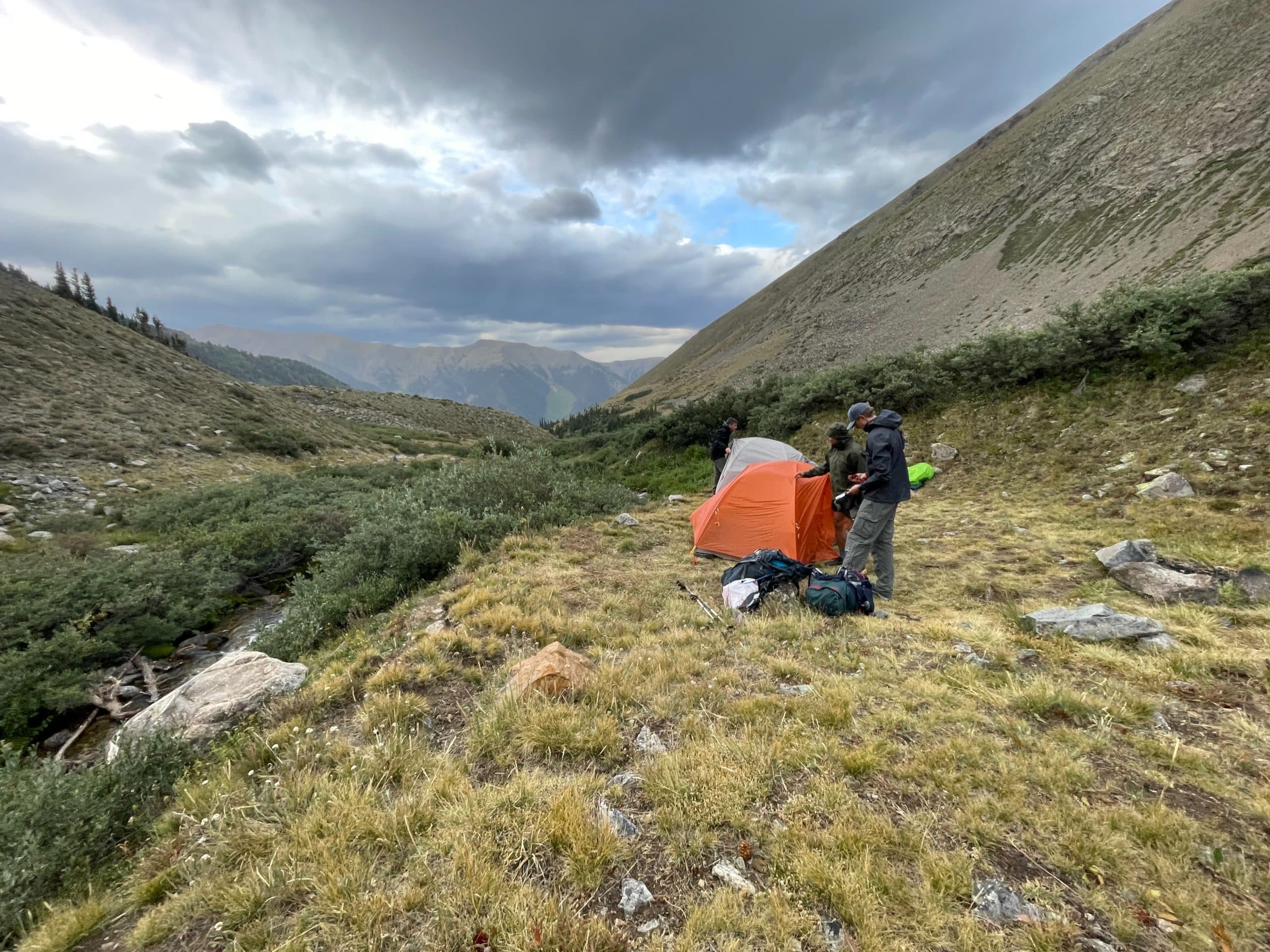 Two hikers pitching the Big Agnes Copper Spur UL2 a rainy alpine environment.