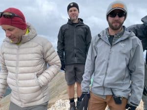 Three men standing on a mountain peak wearing Arc'teryx jackets.