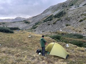 A backpacker standing outside the Nemo Hornet OSMO ultralight backpacking tent.