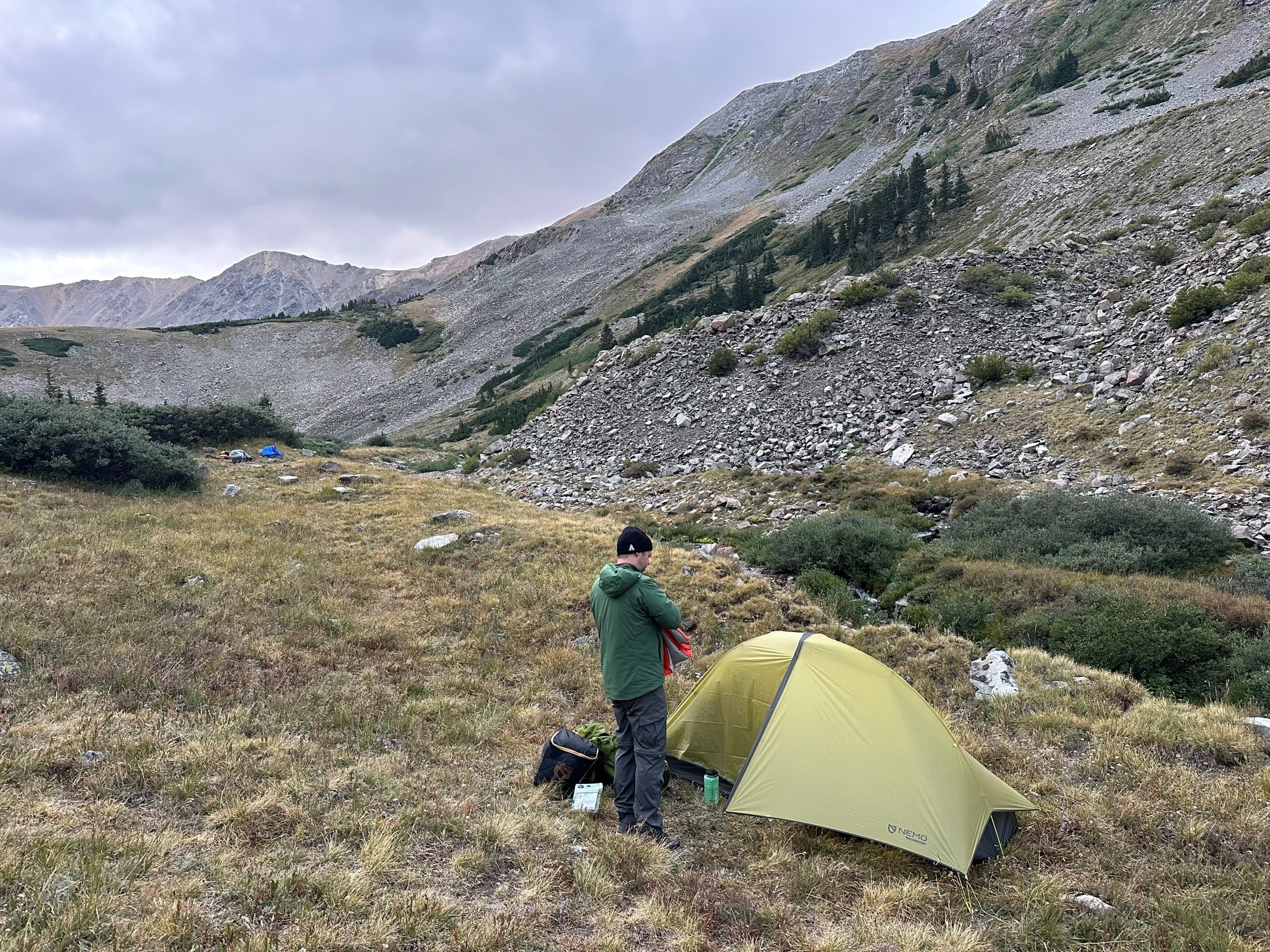 A backpacker standing outside the Nemo Hornet OSMO ultralight backpacking tent.