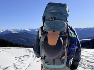 A skier wearing the Osprey Soelden 45L ski pack while looking at a mountain vista.